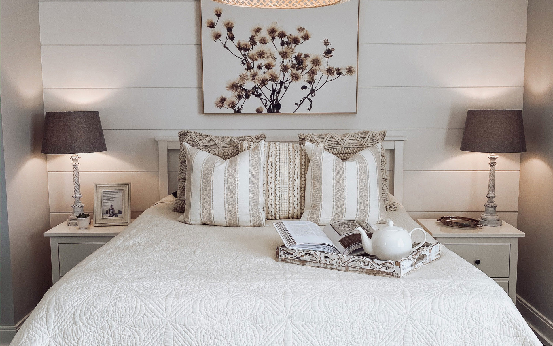 Cozy bedroom with woven light fixture, white bedding, and neutral decor.