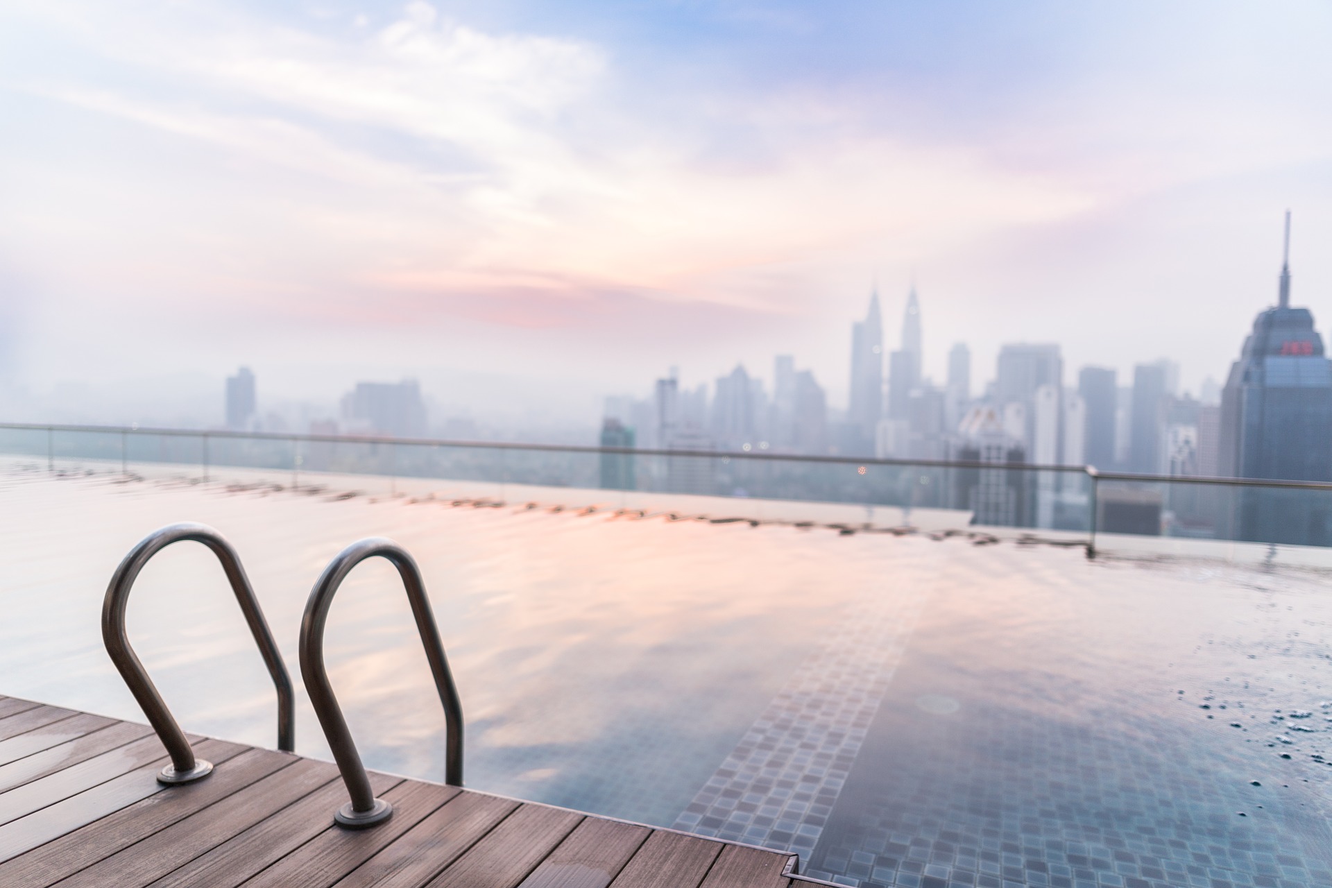 Rooftop pool overlooking city skyline at sunset.