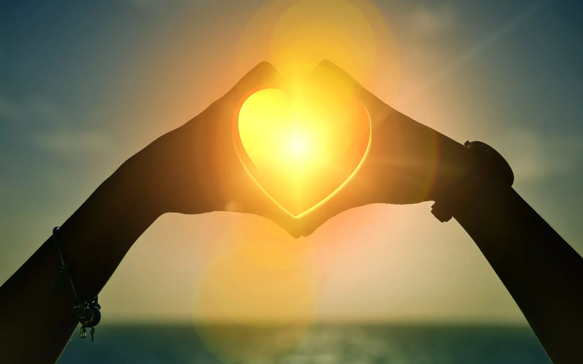 Hands forming a heart shape around the sun.